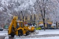 Yellow tractor with snowplow removing snow from the streets