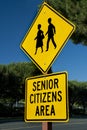 Yellow traffic sign that says Senior Citizens Area with graphic of senior citizens walking along