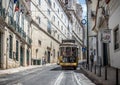 Yellow tram line 28 driving uphill in lisbon