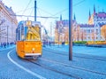 Yellow tram rides along Kossuth Lajos Square, the pedestrin area with Parliament building on background, Budapest, Hungary