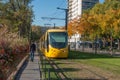 Yellow tramway running near the train station with autumnal trees