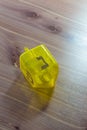 Yellow translucent plastic Hanukkah dreidel on a wood table, Hebrew letter Nun facing up