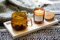 Yellow transparent cup of herbal tea and cozy burning candle with sticker mock-up