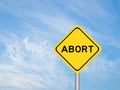 Yellow transportation sign with word abort on blue sky background