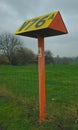 Yellow triangle-shaped pillar in the middle of the street with the inscription V76a in Sint-Pieters-Leeuw, Belgium