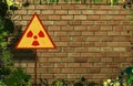 Yellow triangle sign with an international Radioactive Symbol on messy and dirty brick wall background. Digital mock-up