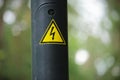 Yellow triangular electricity caution sign on a wire pole