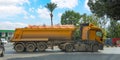 Yellow truck with dump trailer loaded with cargo turns off the road