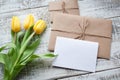 Yellow tulip bouquet and blank greeting card. Top view over wooden table Royalty Free Stock Photo