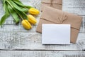 Yellow tulip bouquet and blank greeting card. Top view over wooden table Royalty Free Stock Photo