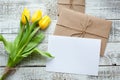 Yellow tulip bouquet and blank greeting card. Top view over wooden table Royalty Free Stock Photo