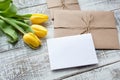 Yellow tulip bouquet and blank greeting card. Top view over wooden table Royalty Free Stock Photo