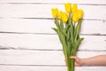 Yellow tulips bunch on white wooden planks rustic barn rural table background. Empty space for lettering, text, letters,
