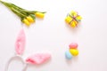 Yellow tulips and colorful Easter eggs gift box, rabbit ears on a white background, top view Royalty Free Stock Photo