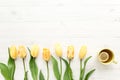 Yellow tulips, cup of tea isolated on a white, wooden background. lay flat, top view Royalty Free Stock Photo