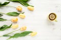 Yellow tulips, cup of tea isolated on a white, wooden background. lay flat, top view Royalty Free Stock Photo