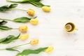 Yellow tulips, cup of tea isolated on a white, wooden background. lay flat, top view Royalty Free Stock Photo