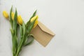 Yellow tulips fresh bright on a white gray textural background with a letter envelope Royalty Free Stock Photo