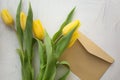 Yellow tulips fresh bright on a white gray textural background with a letter envelope Royalty Free Stock Photo