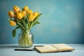 Yellow tulips and a light blue background with a notepad, in the style of understated elegance Royalty Free Stock Photo