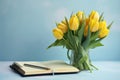 Yellow tulips and a light blue background with a notepad, in the style of understated elegance Royalty Free Stock Photo