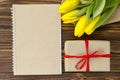 Yellow tulips, notepad, gift box on wooden table Royalty Free Stock Photo