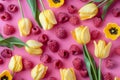yellow tulips and raspberries lay on pink background