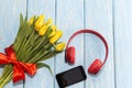 Yellow tulips in a vase with red headphones and a telephone. the concept of romantic music Royalty Free Stock Photo