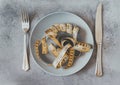 Yellow twisted measuring tape on a brown plate on a gray background, top view, knife, fork, dishes, diet, concept