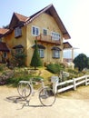 Yellow two-storey house with a garden and bike