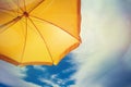 Yellow umbrella against blue sky with clouds