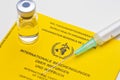 Yellow vaccination document of the world heatlh organization with syringe an vial
