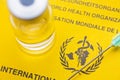 Yellow vaccination document of the world heatlh organization with syringe an vial