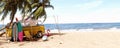 Yellow van with summer accessories on beautiful tropical sand beach. Summer travel concept background. Royalty Free Stock Photo
