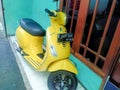 yellow vespa metic scooter parked in front of the house