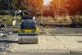 Yellow vibration road roller compacting ground and stone on construction site. Road work and road construction Royalty Free Stock Photo