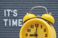 yellow vintage alarm clock on a gray felt Board background with English text