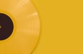 Yellow Vinyl Record with a Black Label on a Flat Yellow Surface. Summer Music Background with Copy Space.