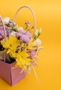 Yellow-violet flower arrangement in a box of chrysanthemums, eustomas, cotton inflorescences and dried flowers on a yellow Royalty Free Stock Photo