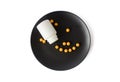 Yellow vitamins pills on a black plate on a white isolated background. Breakfast pills. Royalty Free Stock Photo