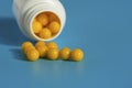 Yellow vitamins pour out from a pill bubble on a blue background. Vitamin complex. Multivitamins to enhance health and immunity