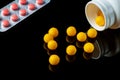 Yellow vitamins are sprinkled from a white bottle and pills on a black isolated background. Free advertising space Royalty Free Stock Photo