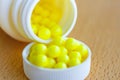 Yellow vitamins in a white plastic bottle cap on the table closeup Royalty Free Stock Photo