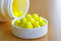 Yellow vitamins in a white plastic bottle cap on the table closeup Royalty Free Stock Photo