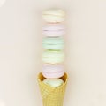 Yellow waffle cone with green, pink and yellow marshmallows looks like macaroons on pastel background Royalty Free Stock Photo