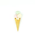 Yellow waffle cone with green, pink and yellow marshmallows looks like macaroons on white background Royalty Free Stock Photo