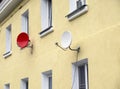 Yellow wall of a two-story residential building and two modern satellite dishes