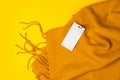 Beautiful yellow warm winter scarf with label tag mockup template on yellow background with space for text, top view Royalty Free Stock Photo