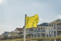 Yellow warning flag on a pole against the view of beach houses and sky at Destin, Florida Royalty Free Stock Photo