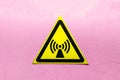 Yellow warning sign electromagnetic field on a pink background